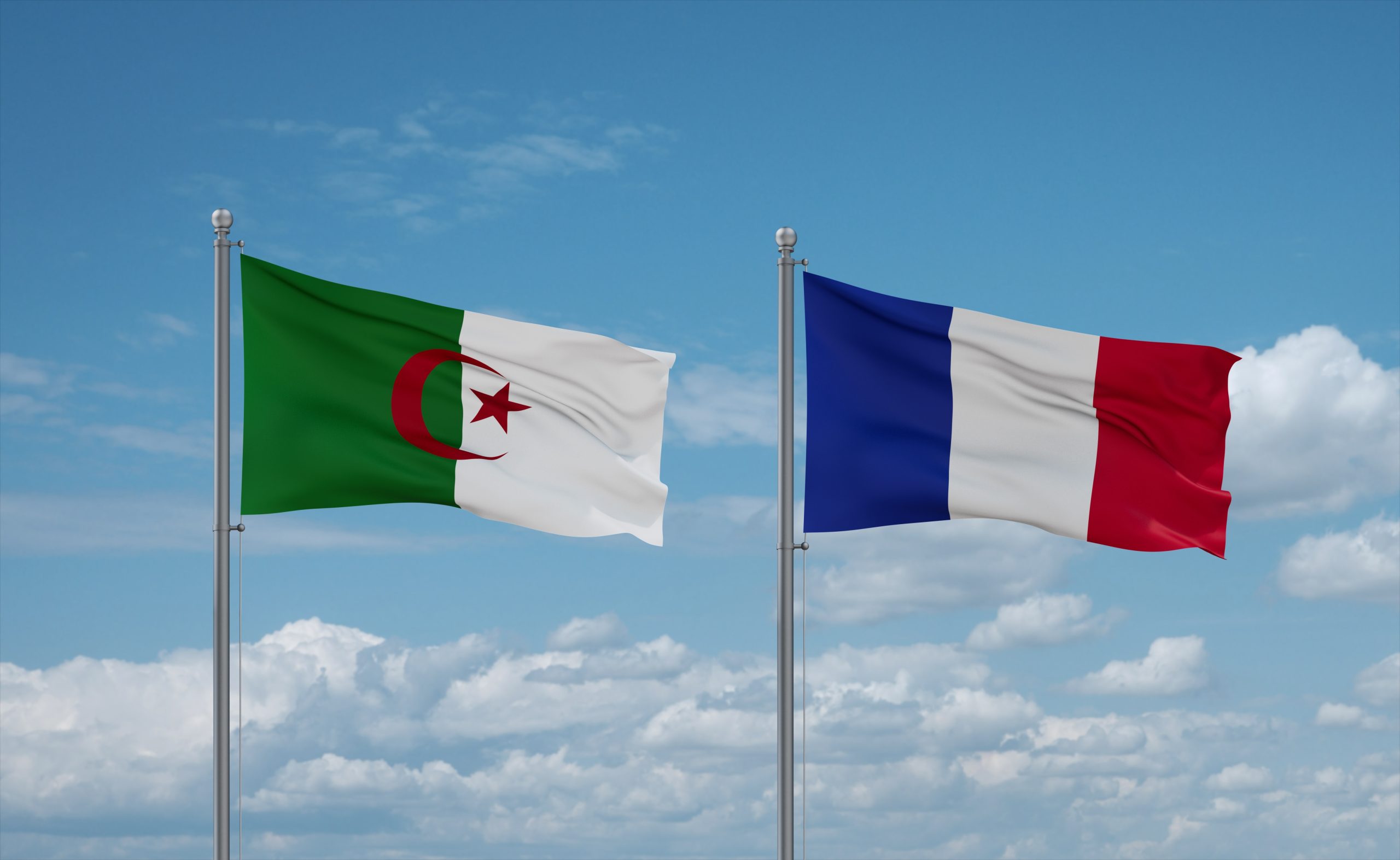 Banderas de Argelia y Francia ondean juntas en cielo azul nublado. / Shutterstock / iunewind